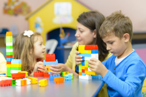 Kids playing with plastic building blocks at kindergarten