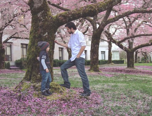 felnőttel beszélgető kislány, fák alatt