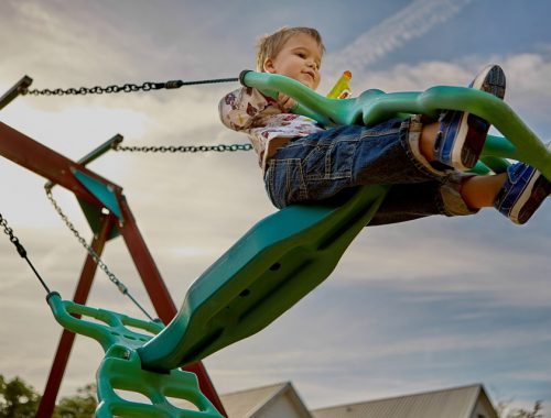 kisfiú hintázik a játszótéren