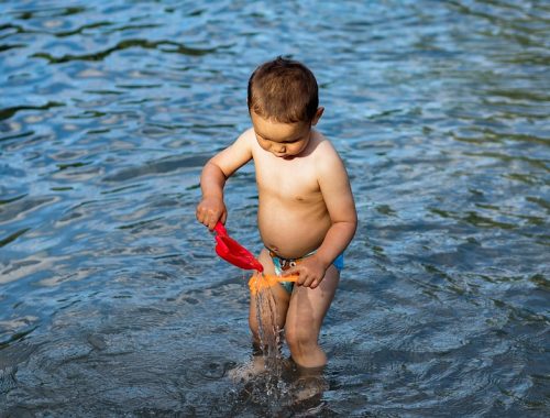 kisfiú játszik a vízben fürdőnadrágban