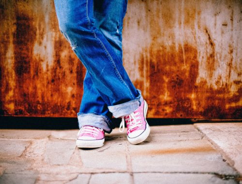 kislány keresztbe tett lábbal, rózsaszín tornacipővel