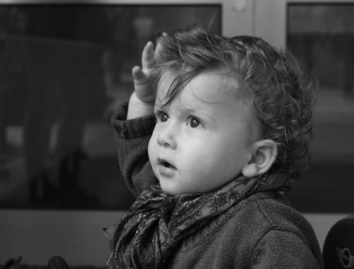 kisbaba feje felé emeli a kezét