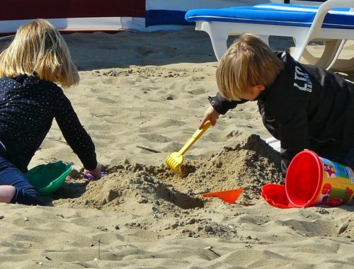 két gyerek játszik a tengerparti homokban