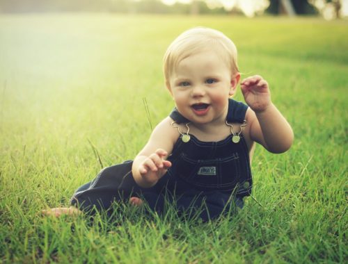 kisfiú ül a fűben