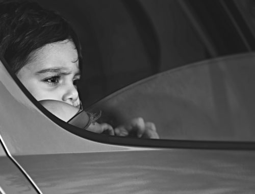 fekete-fehér gyerek aggódóan néz ki az autóból