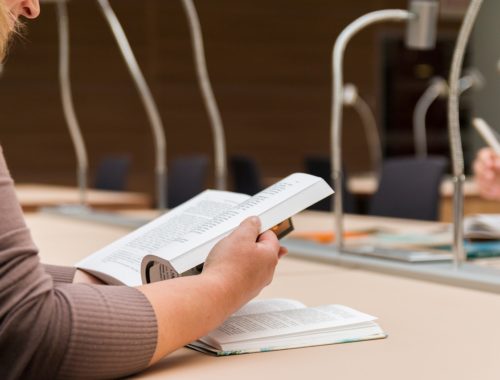 nő egy könyvvel és lámpákkal