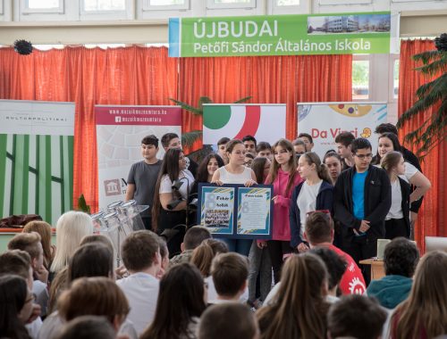 kisiskolások csoportban állnak, előadást tartanak