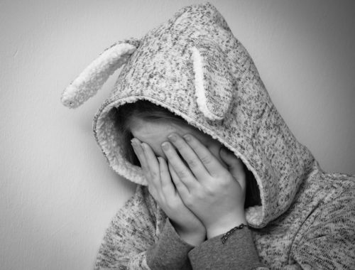 nyuszis pulcsiban arcát fogó kislány