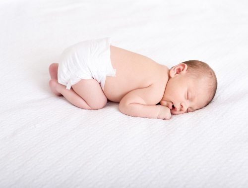 csecsemő alszik egy fehér takarón