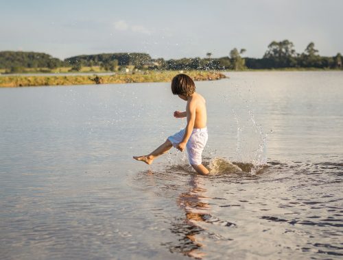 kisfiú játszik a vízben fürdőnadrágban
