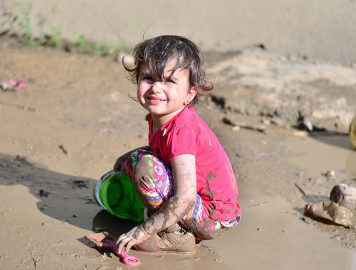 kislány játszik a kavicsos vízparton