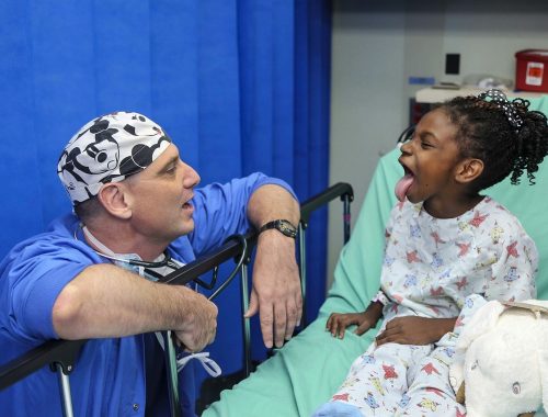 orvos vizsgálja a beteg kislányt, aki kinyújtja a nyelvét