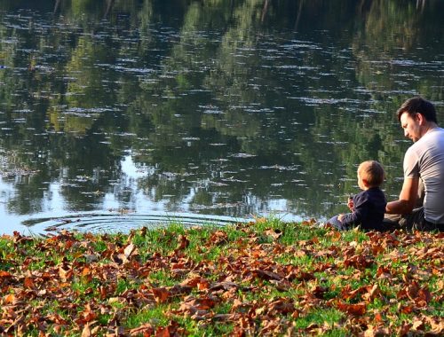 kisfiú ül a tó partján az apukájával
