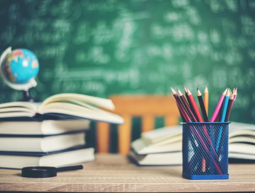 asztalon lévő könyvek, ceruzák és egy Föld gömb