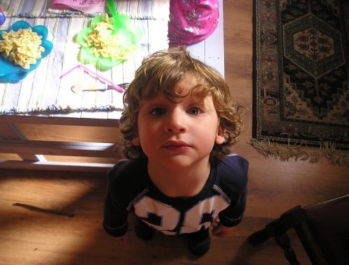 kisfiú áll egy asztal mellett