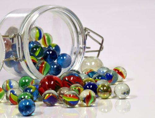 színes üveggolyók kigurulnak egy befőttes üvegből