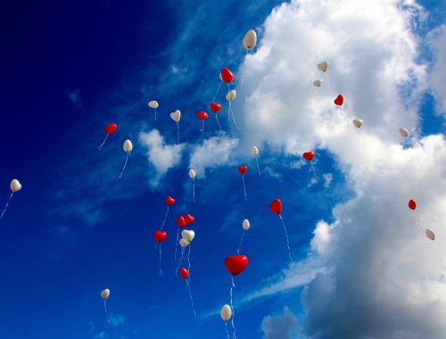 Szív lufik repülnek az égen.